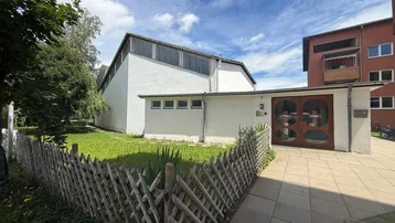 Außenansicht des Gebäudes mit weißer Fassade, kleinem Gartenbereich und Holzzaun.