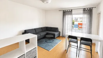 Heller Wohn- und Essbereich mit Ecksofa, Esstisch und Zugang zum Balkon.