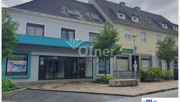 Gebäudeansicht mit mehreren Geschäftsfronten und Ofner Immobilien Beschilderung an der Fassade.