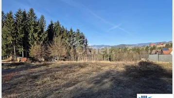 Weitläufiges Grundstück mit Blick auf die umliegende Natur und entfernte Berge unter blauem Himmel.