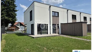Moderne Reihenhäuser mit weißer Fassade, Holzdetails und kleinem Vorgarten unter blauem Himmel.