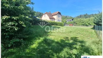 Großes Grundstück mit viel Grünfläche und einem Haus im Hintergrund unter blauem Himmel.