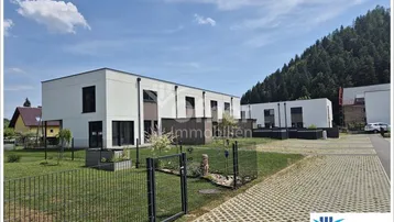 Moderne Reihenhäuser mit weißer Fassade und Holzdetails in grüner Umgebung.