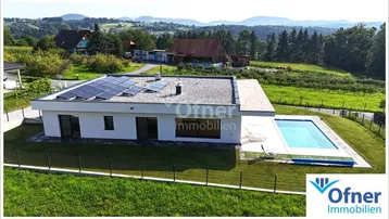 Moderne Villa mit Flachdach, Solaranlage und großem Pool in ländlicher Umgebung.