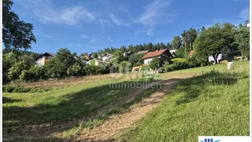 Weitläufiges Grundstück mit leichter Hanglage und Blick auf umliegende Häuser und grüne Landschaft.