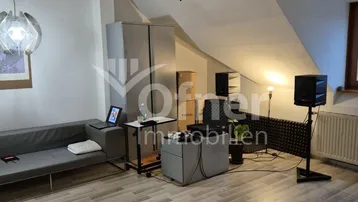 Helles Wohnzimmer mit Dachschrägen, modernem Laminatboden und gemütlicher Sitzecke.