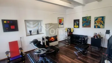 Gemütliches Wohnzimmer mit Kamin, dunklen Möbeln und Kunstwerken an den Wänden.