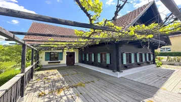 Große Holzterrasse mit Pergola und Weinreben, ideal für entspannte Stunden im Freien.