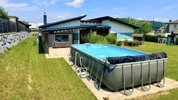 Großer Garten mit einem Aufstellpool und Blick auf das moderne Wohnhaus.