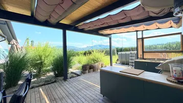 Geräumige überdachte Terrasse mit Außenküche, Holzboden und Panoramablick.