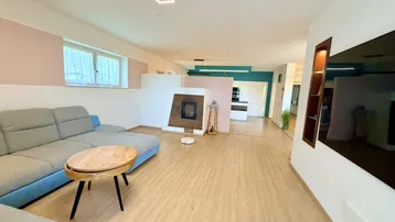 Offener Wohnbereich mit Sofa, Kamin und Blick auf die moderne Küche.