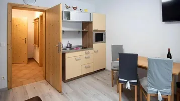 Kleine Küchenzeile mit Essbereich und hellem Laminatboden in einem gemütlichen Raum.