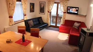 Gemütlicher Wohn-Essbereich mit Esstisch, Sofas und Zugang zu einem Balkon, ausgestattet mit Teppichboden.