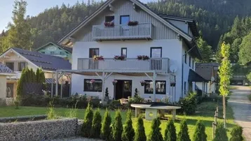 Charmantes Haus mit mehreren Balkonen, überdachter Terrasse und gepflegtem Garten in den Bergen.