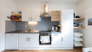 Moderne Einbauküche mit weißen Schränken, Spülmaschine und Kochfeld.
