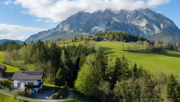 Haus in idyllischer Lage mit beeindruckendem Bergblick und umgeben von grünen Wäldern.