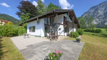 Große gepflasterte Terrasse mit Gartenmöbeln vor dem Haus und Blick auf die umliegende Natur.