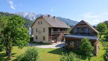 Traditionelles Holzhaus mit Bergblick und großem Garten in ländlicher Umgebung.