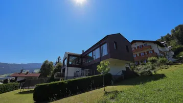 Modernes Wohnhaus mit großen Glasflächen und sonniger Hanglage.