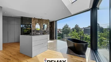 Exklusives Schlafzimmer mit Doppelwaschbecken, freistehender Badewanne und Panoramablick.