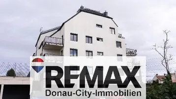 Modernes Mehrfamilienhaus mit weißer Fassade und Balkonen unter bewölktem Himmel.