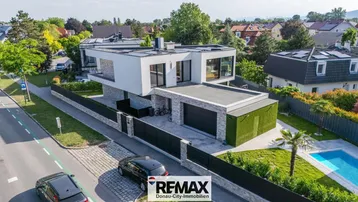 Moderne Villa mit Flachdach, großem Garten und privatem Pool in einer Wohngegend.