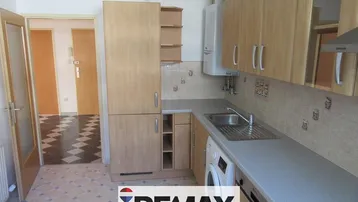Funktionale Küche mit Holzschränken, Spüle und Waschmaschine, Blick in den Flur.