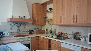 Traditionelle Küche mit Holzschränken, weißen Arbeitsplatten und integrierten Geräten, gut gepflegt.