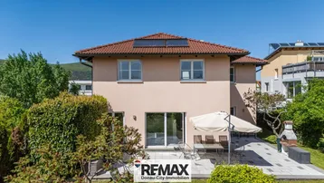 Rückseite des Hauses mit sonniger Terrasse, Grillbereich und Photovoltaikanlage auf dem Dach.