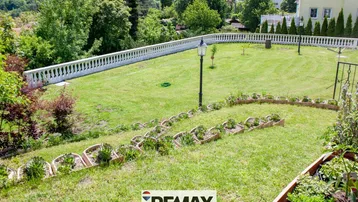Terrassierter Gartenbereich mit Rasen, Blumenbeeten und einer Balustrade mit weitem Blick.