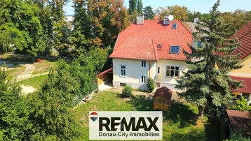 Luftaufnahme eines Einfamilienhauses mit rotem Ziegeldach und großem, grünen Gartenbereich.
