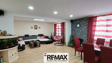 Geräumiger Wohn- und Essbereich mit Holzboden und Aquarium, ideal für Familien.