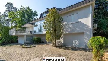 Die Vorderseite des Hauses mit gepflasterter Auffahrt, Garage und großen Fenstern.