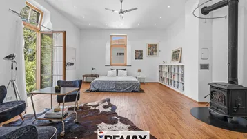 Geräumiges Schlafzimmer mit Holzboden, Kaminofen und Zugang zu einem Balkon.