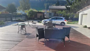 Große Holzterrasse mit Sitzgelegenheiten und Blick auf die umliegende Berglandschaft.
