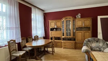 Geräumiger Wohn-Essbereich mit traditionellen Holzmöbeln, roten Wänden und hellem Parkettboden.