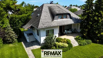 Gepflegtes Einfamilienhaus mit Satteldach, umgeben von einem grünen Garten und einer kleinen Terrasse.
