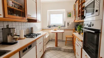 Funktionale Küche mit weißen Schränken, Holzarbeitsplatten und integrierten Geräten.