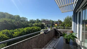 Sonniger Balkon mit Blick ins Grüne und einem kleinen Tisch für entspannte Stunden.
