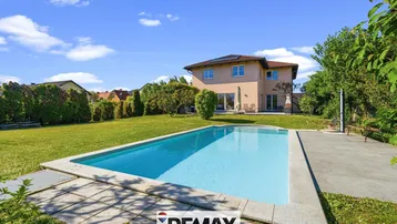 Haus mit großem Garten, Swimmingpool und sonniger Terrasse im Hintergrund.