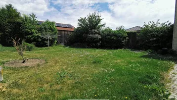 Hinterhofbereich mit Rasen, Wäscheleine und einem Schuppen mit Solaranlage.