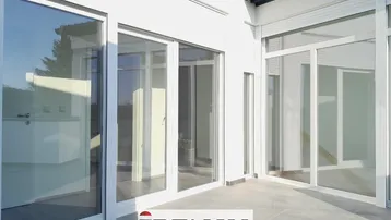 Große, geflieste Terrasse mit Zugang zu den Innenräumen durch bodentiefe Fenster.