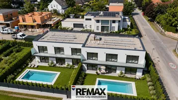 Luftaufnahme von zwei modernen Häusern mit Pools und Solaranlagen auf den Dächern.