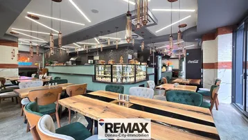 Geräumiger Restaurantbereich mit modernen Holztischen, bequemen Stühlen und einer Theke mit Auslage.