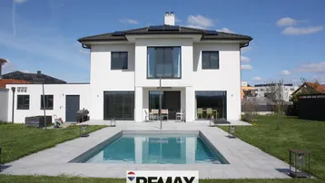 Modernes Einfamilienhaus mit privatem Pool, Garten und Solaranlage auf dem Dach.