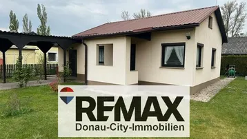 Einfamilienhaus mit beiger Fassade, braunem Dach und gepflegtem Vorgarten.