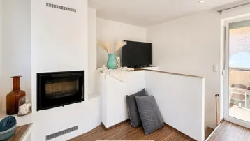 Gemütlicher Wohnbereich mit modernem Kamin und Zugang zu einem Außenbereich.