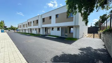 Reihe moderner Reihenhäuser mit weißer und beiger Fassade unter blauem Himmel.