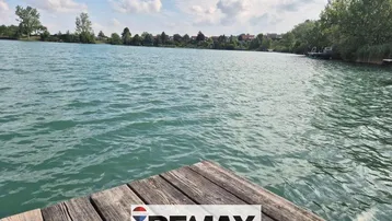 Idyllischer Blick auf den See von einem Holzsteg aus, umgeben von grüner Natur.