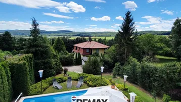 Weitläufiges Anwesen mit Pool und Fernblick über die grüne Landschaft unter blauem Himmel.